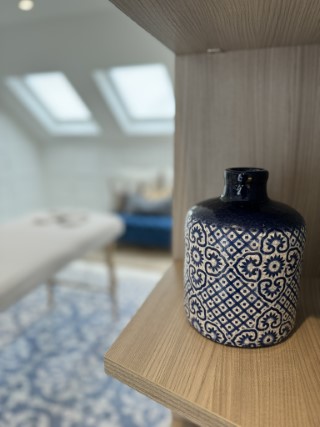 A close-up of a blue and white ceramic vase with a massage table in the background.